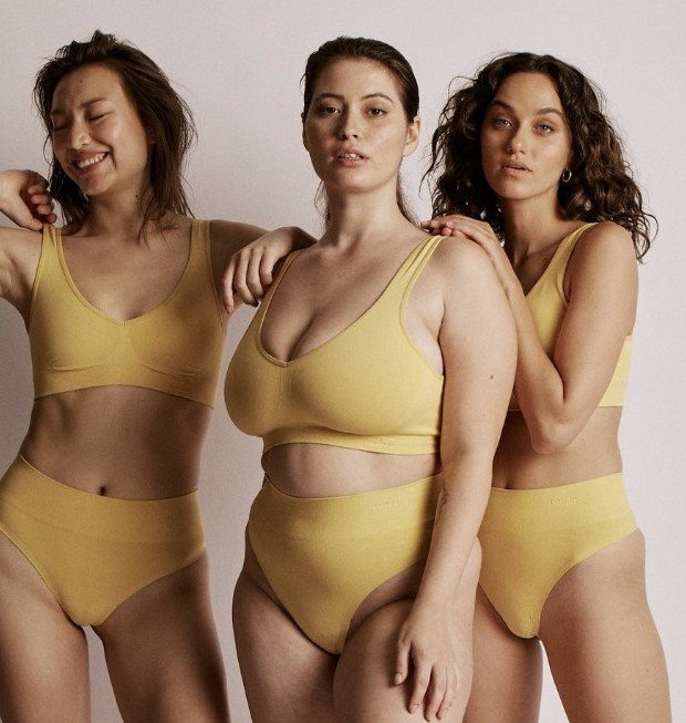 Three women in yellow sets standing together, smiling and relaxed